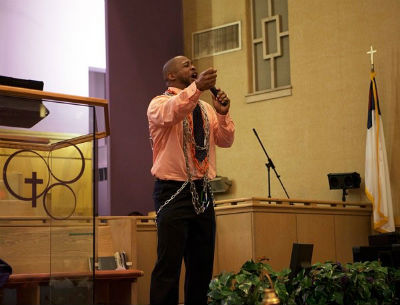 Photo: Kevin preaches while illustrating spiritual bondage.