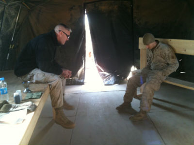 Photo: Chaplain Miller prays with a young Marine in Afghanistan.